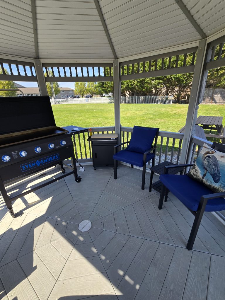 Outdoor patio with grill and blue seating under gazebo shade